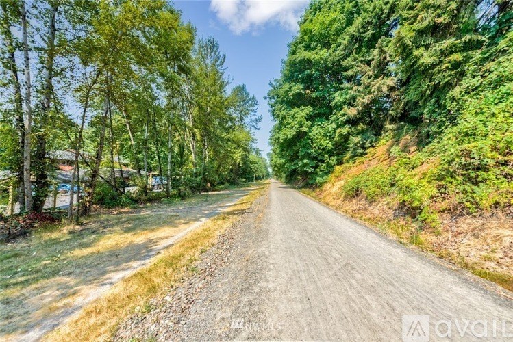 A gravel road stretches into the distance surrounded by trees.