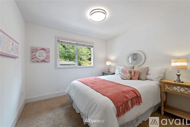 A bedroom with a bed, a window, and a carpet.