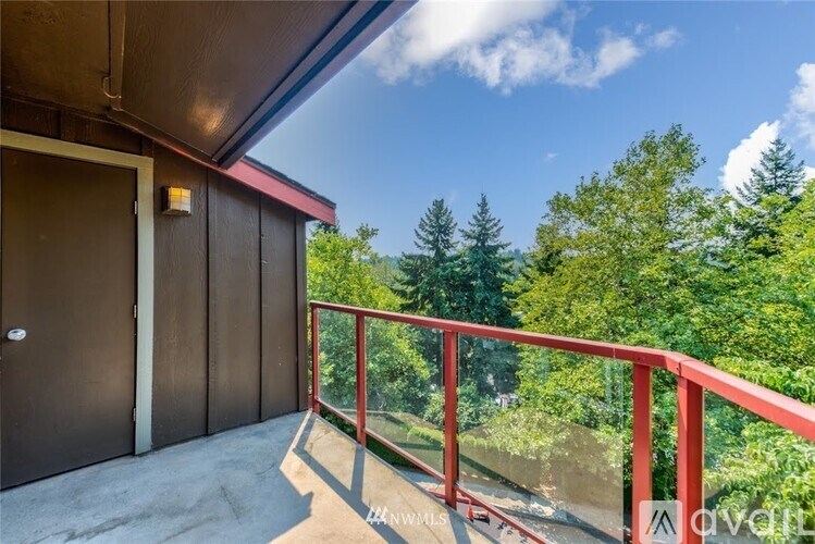 A balcony with a red railing and a view of trees.