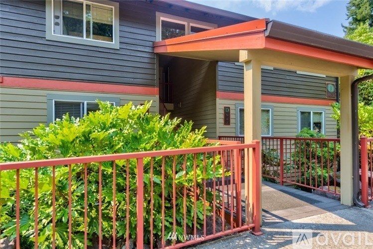 A house with a red fence and green plants in front.