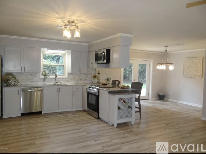 A kitchen with white cabinets and a wooden island.
