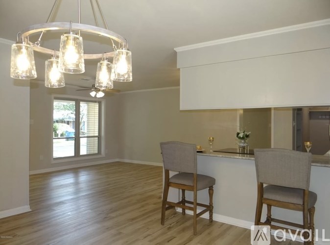 A well-lit kitchen with wooden floors and a bar area with two chairs.