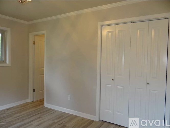 A room with a white door and a white closet with a window.