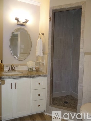 A bathroom with a marble counter top and a glass shower door.
