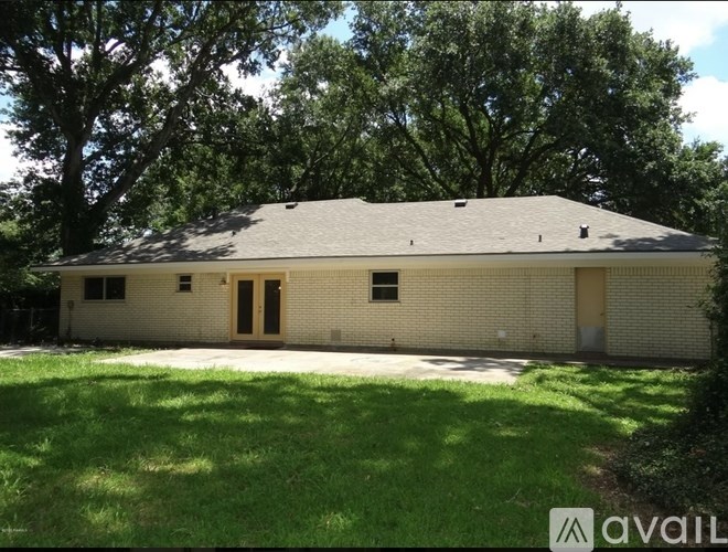 A house with a grassy front yard and trees in the background.