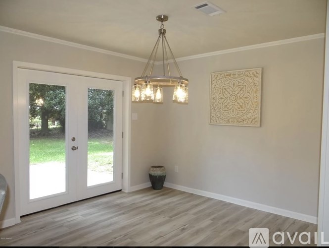 A room with a chandelier, a door, and a wall hanging.