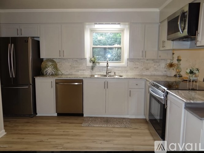 A kitchen with white cabinets and a wooden floor.