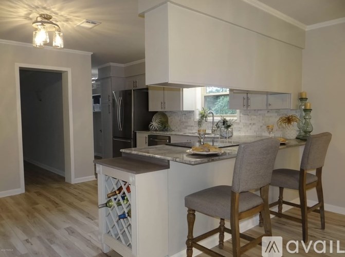 A kitchen with a white countertop and wooden chairs.