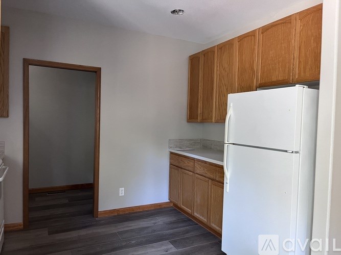 A kitchen with a white refrigerator and wooden cabinets.