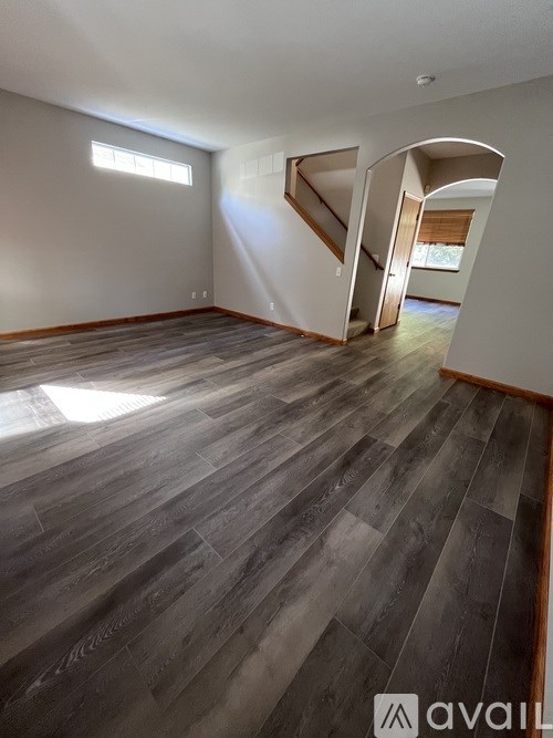 A room with wooden flooring and a staircase leading to another room.