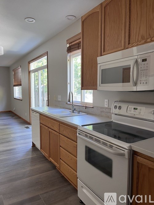 A kitchen with wooden cabinets and a white microwave above the stove.