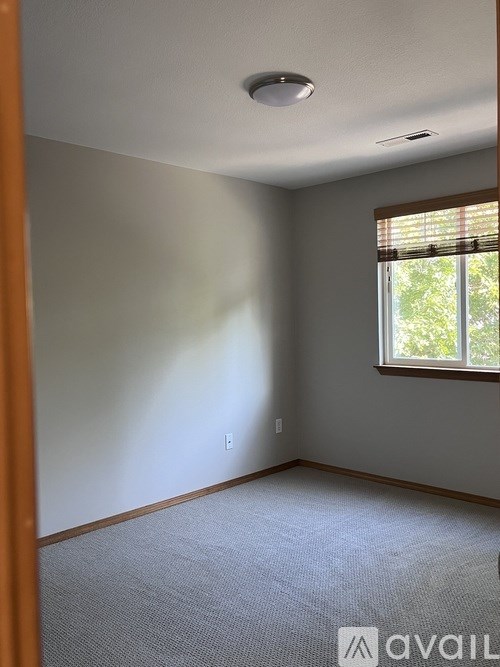 A room with a window and a carpeted floor.
