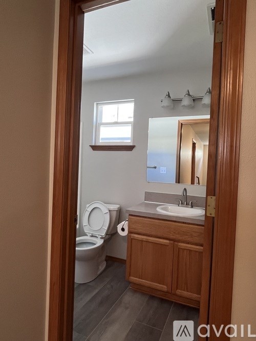 A bathroom with a toilet, sink, and mirror.