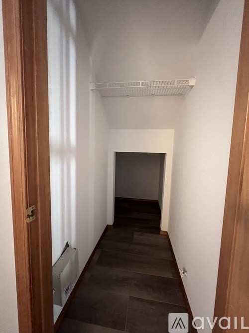 A long hallway with a door on the left and a shelf on the right.