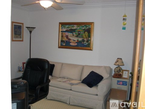 A living room with a couch, chair, and a painting on the wall.