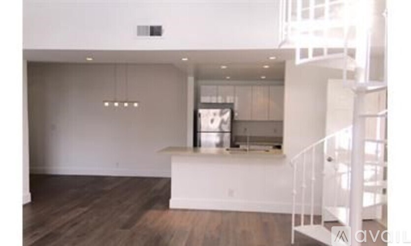 A white staircase with a metal railing leads to a second floor.
