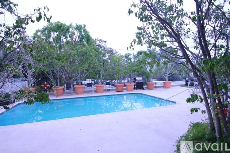 A pool surrounded by trees and chairs.
