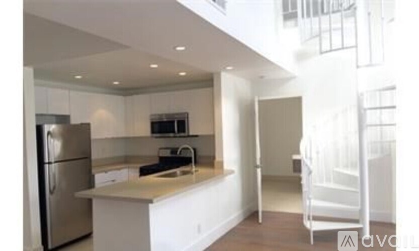 A kitchen with white cabinets and a stainless steel refrigerator.