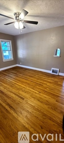 A room with a ceiling fan and wooden flooring.