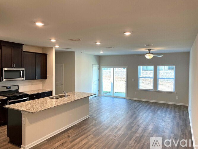 A spacious kitchen with dark wood cabinets and a granite countertop.