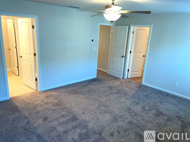 A room with a carpeted floor and a ceiling fan.