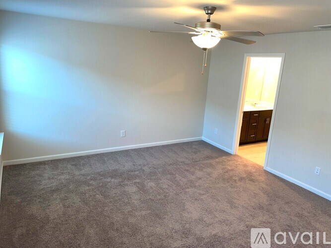 A room with a carpeted floor and a ceiling fan.