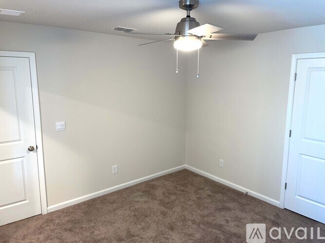 A room with a ceiling fan and carpeted floor.