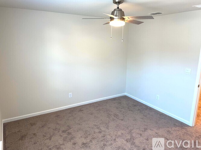 A room with a ceiling fan and carpeted floor.