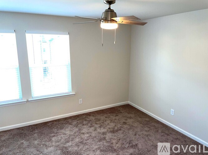 A room with a carpet floor, a ceiling fan, and a window.