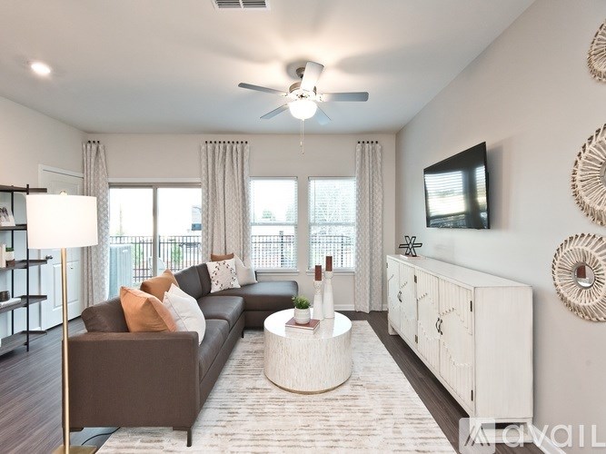 A living room with a brown couch, a white coffee table, and a flat screen TV mounted on the wall.
