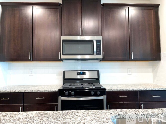 A kitchen with dark brown cabinets and a stove top oven.