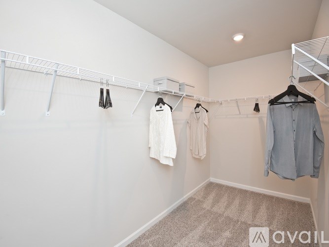 A white closet with clothes hanging on a rail.