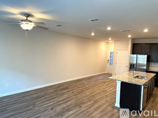 A room with a ceiling fan and a kitchenette is available for rent.