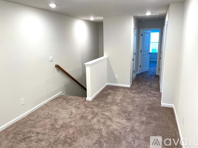 A carpeted room with a staircase leading to another room.