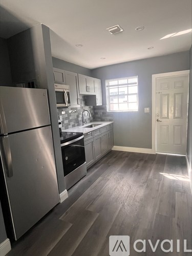 A kitchen with a stainless steel refrigerator and wooden flooring.