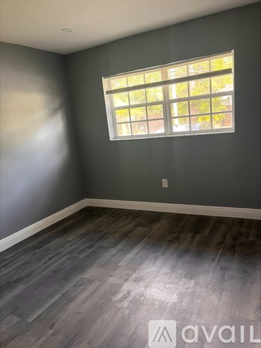 A room with a grey wall and a window with blinds.