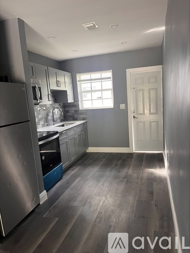 A kitchen with a refrigerator, cabinets, and a door.