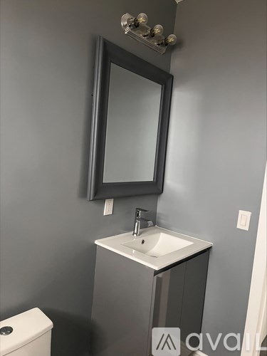 A bathroom with a sink, mirror, and toilet.