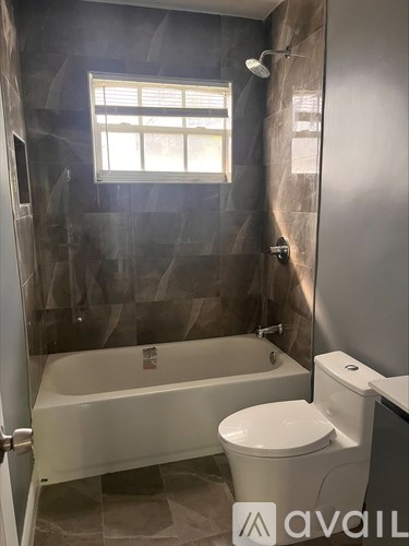 A bathroom with a toilet, tub, and window.