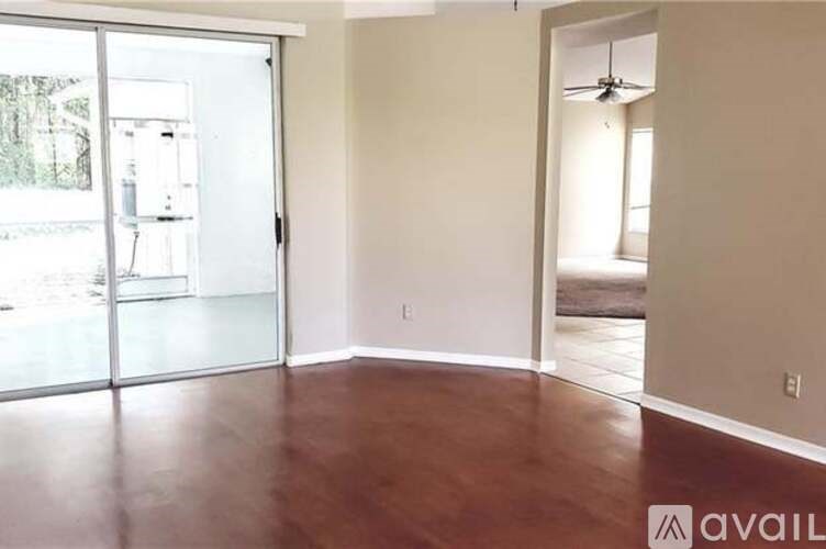 A room with a sliding glass door and wooden flooring.