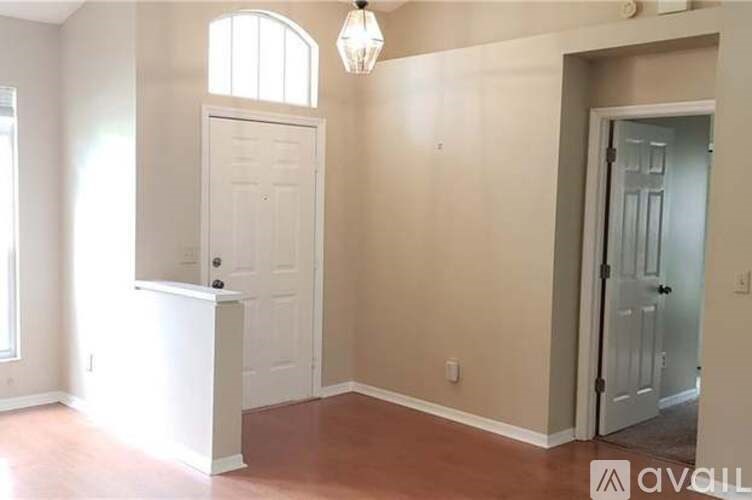 A room with a white door and a window with a chandelier hanging from the ceiling.