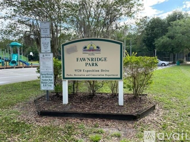 A sign for Fawnridge Park is displayed in front of a playground.