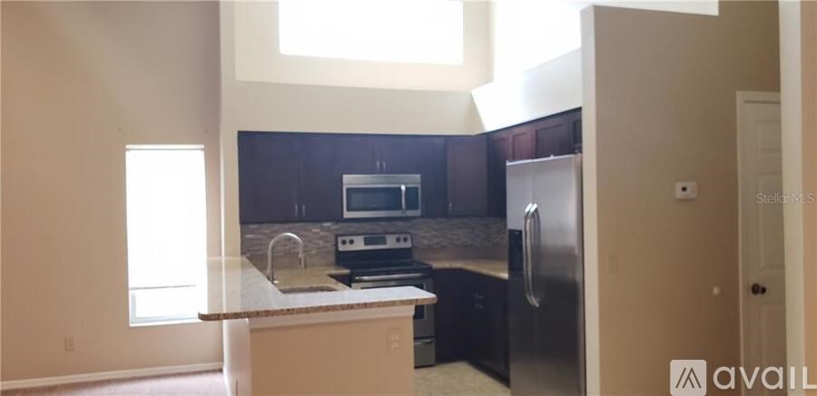 A kitchen with a black refrigerator and a stove top oven.