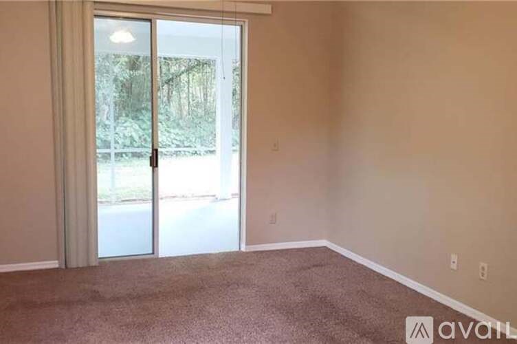 A room with a carpeted floor and a sliding glass door leading outside.