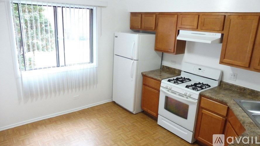 A kitchen with white appliances and wooden cabinets.