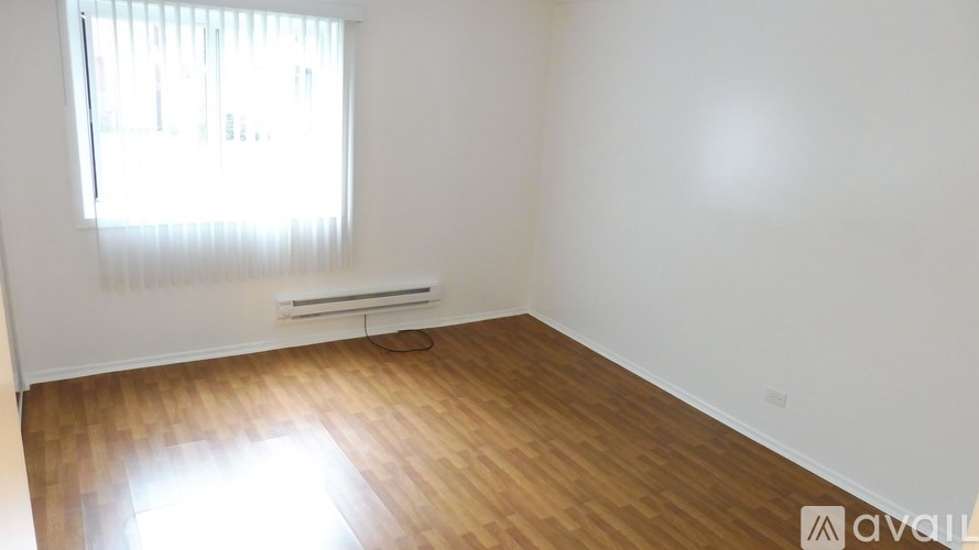 A room with wooden flooring and a window with blinds.