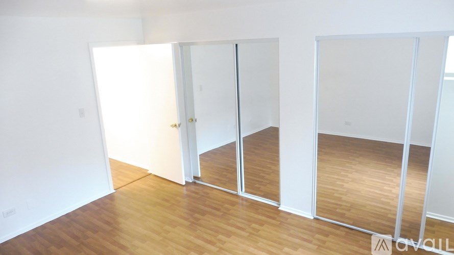 A room with white walls and wooden flooring, with a white door in the middle.