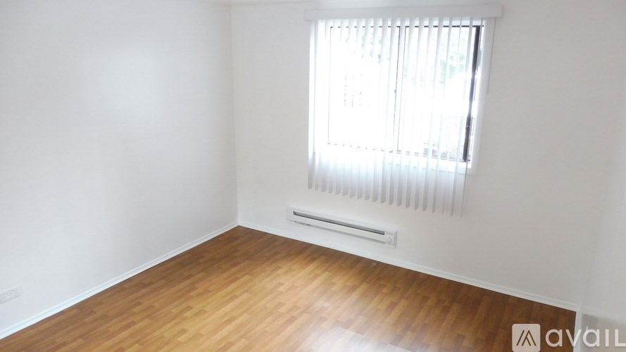 A room with wooden flooring and a window with blinds.
