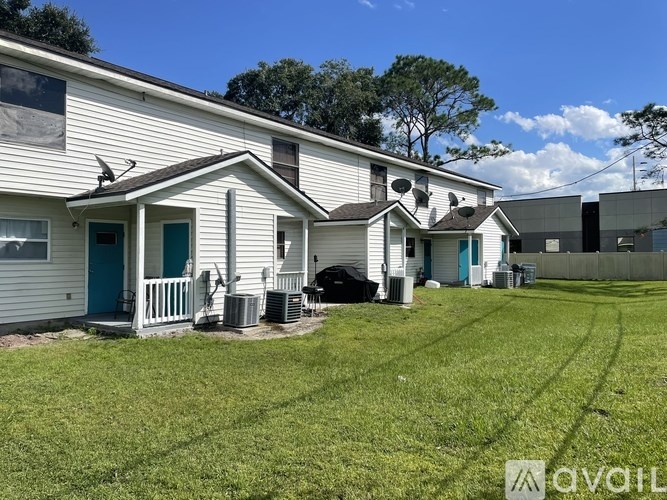 A house with a blue door and a white siding is surrounded by a green lawn.