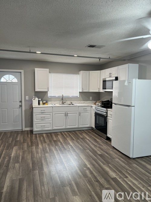 A kitchen with white appliances and wooden floors.